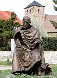 Bronzeplastik des Ostfalenführers Hessi vor dem Kloster Wendhusen. Im Hintergrund ist der Turm der St. Andreas Kirche zu sehen.